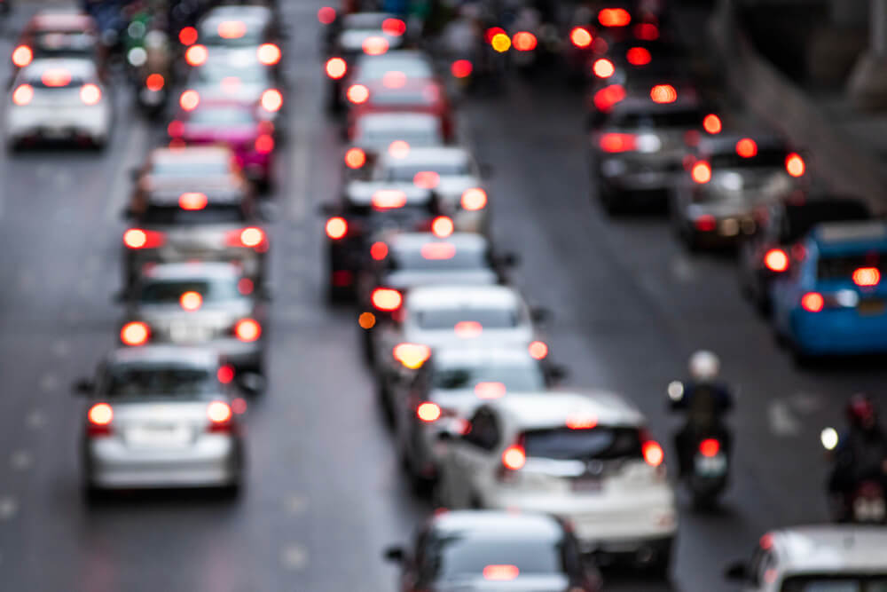 Starker Stadtverkehr mit Autos, Motorrädern und roten Bremslichtern im Abendlicht, unscharf wie ein automatisch gespeicherter Entwurf